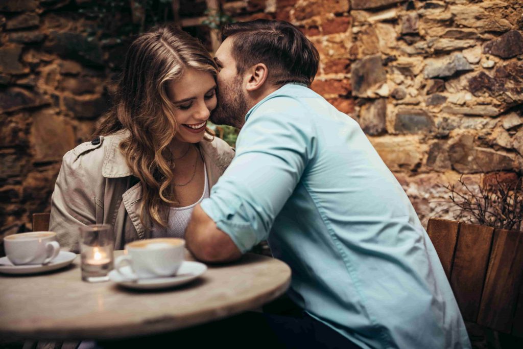 Man Whispering In Womans Ear On A Date