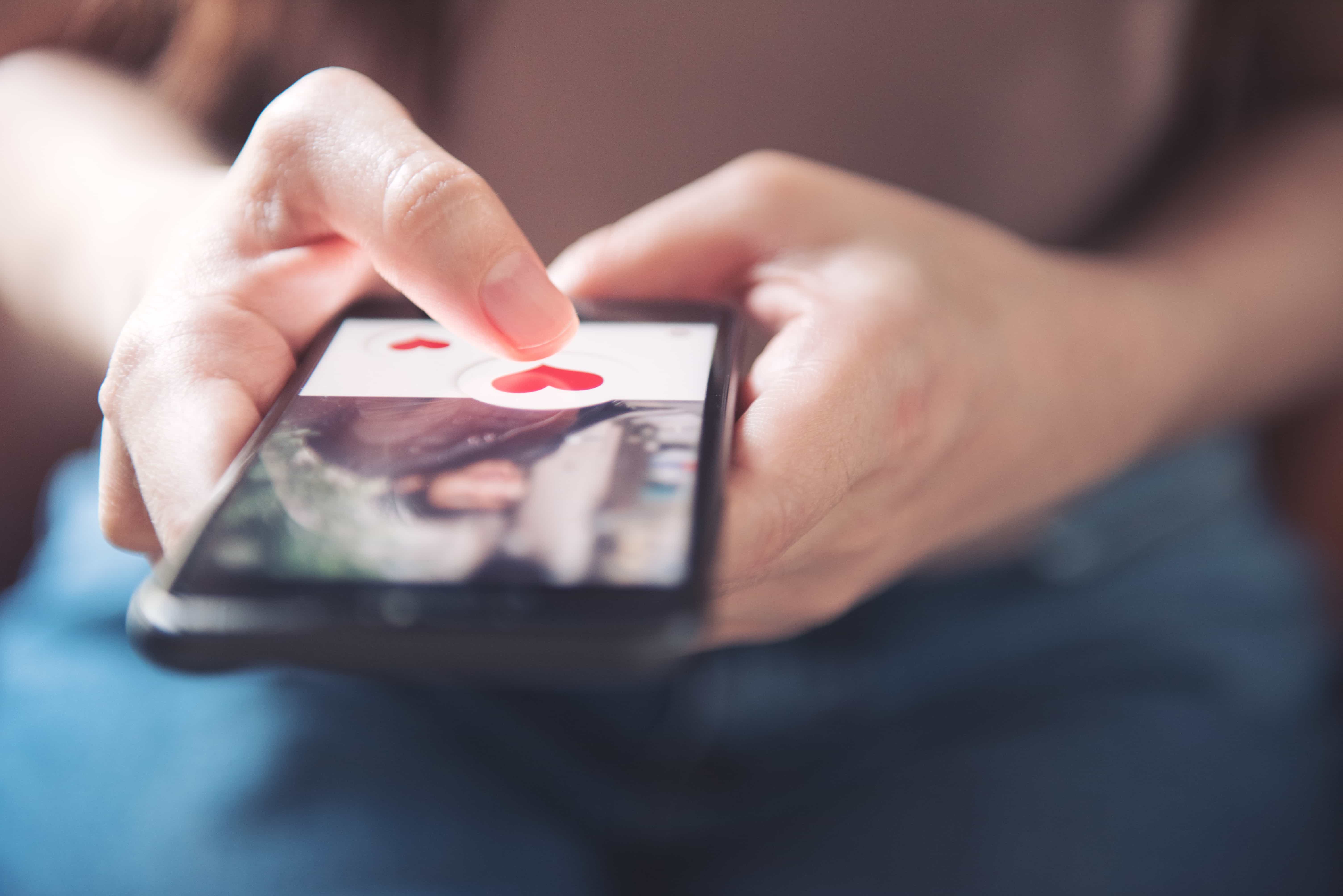 man holding phone with dating app on it